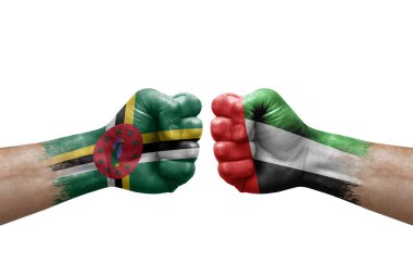 Two hands punch to each others on white background. Country flags painted fists, conflict crisis concept between dominica and united arab emirates