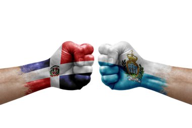 Two hands punch to each others on white background. Country flags painted fists, conflict crisis concept between dominican republic and san marino