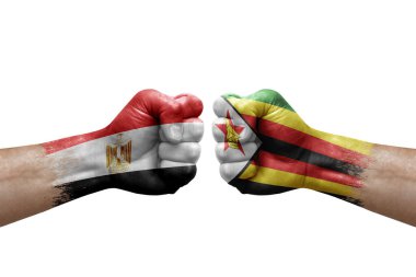 Two hands punch to each others on white background. Country flags painted fists, conflict crisis concept between egypt and zimbabwe