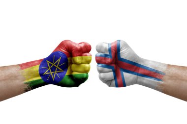 Two hands punch to each others on white background. Country flags painted fists, conflict crisis concept between ethiopia and faroe islands