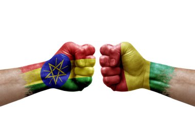 Two hands punch to each others on white background. Country flags painted fists, conflict crisis concept between ethiopia and guinea