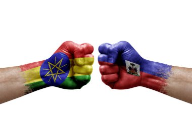 Two hands punch to each others on white background. Country flags painted fists, conflict crisis concept between ethiopia and haiti