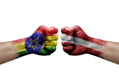 Two hands punch to each others on white background. Country flags painted fists, conflict crisis concept between ethiopia and latvia