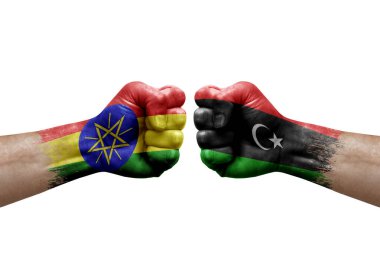 Two hands punch to each others on white background. Country flags painted fists, conflict crisis concept between ethiopia and libya
