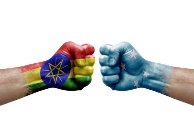 Two hands punch to each others on white background. Country flags painted fists, conflict crisis concept between ethiopia and micronesia