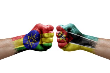 Two hands punch to each others on white background. Country flags painted fists, conflict crisis concept between ethiopia and mozambique