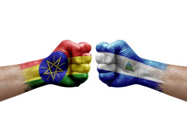 Two hands punch to each others on white background. Country flags painted fists, conflict crisis concept between ethiopia and nicaragua