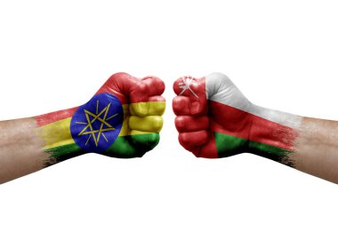 Two hands punch to each others on white background. Country flags painted fists, conflict crisis concept between ethiopia and oman