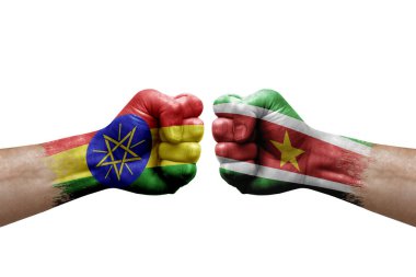 Two hands punch to each others on white background. Country flags painted fists, conflict crisis concept between ethiopia and suriname