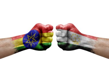 Two hands punch to each others on white background. Country flags painted fists, conflict crisis concept between ethiopia and tajikistan