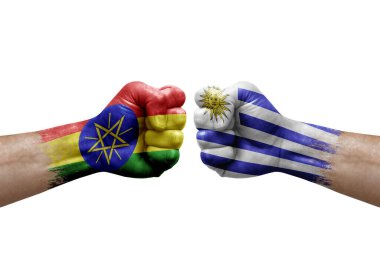 Two hands punch to each others on white background. Country flags painted fists, conflict crisis concept between ethiopia and uruguay