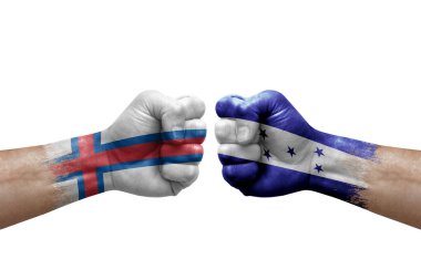 Two hands punch to each others on white background. Country flags painted fists, conflict crisis concept between faroe islands and honduras
