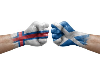 Two hands punch to each others on white background. Country flags painted fists, conflict crisis concept between faroe islands and scotland