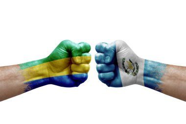 Two hands punch to each others on white background. Country flags painted fists, conflict crisis concept between gabon and guatemala
