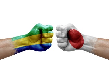 Two hands punch to each others on white background. Country flags painted fists, conflict crisis concept between gabon and japan