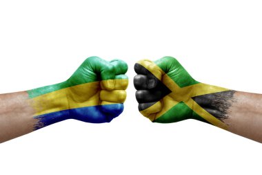 Two hands punch to each others on white background. Country flags painted fists, conflict crisis concept between gabon and jamaica