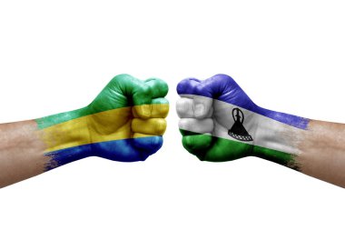 Two hands punch to each others on white background. Country flags painted fists, conflict crisis concept between gabon and lesotho
