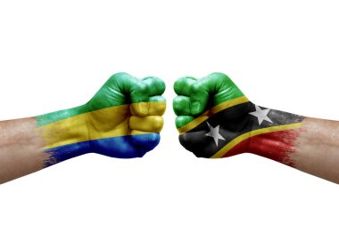 Two hands punch to each others on white background. Country flags painted fists, conflict crisis concept between gabon and saint kitts and nevis