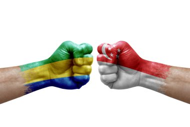 Two hands punch to each others on white background. Country flags painted fists, conflict crisis concept between gabon and singapore