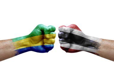 Two hands punch to each others on white background. Country flags painted fists, conflict crisis concept between gabon and thailand