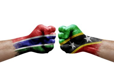 Two hands punch to each others on white background. Country flags painted fists, conflict crisis concept between gambia and saint kitts and nevis