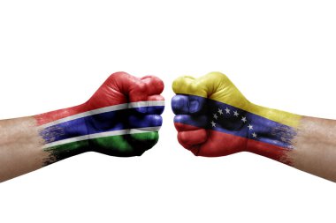 Two hands punch to each others on white background. Country flags painted fists, conflict crisis concept between gambia and venezuela
