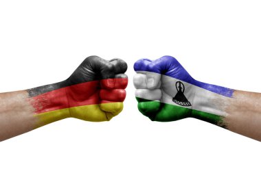 Two hands punch to each others on white background. Country flags painted fists, conflict crisis concept between germany and lesotho