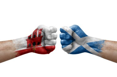 Two hands punch to each others on white background. Country flags painted fists, conflict crisis concept between gibraltar and scotland