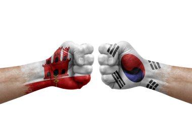 Two hands punch to each others on white background. Country flags painted fists, conflict crisis concept between gibraltar and south korea