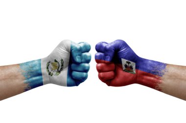 Two hands punch to each others on white background. Country flags painted fists, conflict crisis concept between guatemala and haiti