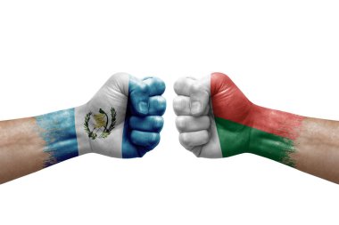 Two hands punch to each others on white background. Country flags painted fists, conflict crisis concept between guatemala and madagascar