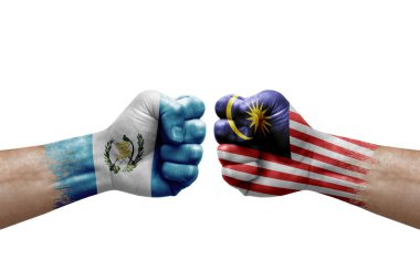 Two hands punch to each others on white background. Country flags painted fists, conflict crisis concept between guatemala and malaysia