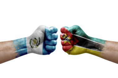 Two hands punch to each others on white background. Country flags painted fists, conflict crisis concept between guatemala and mozambique