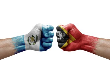 Two hands punch to each others on white background. Country flags painted fists, conflict crisis concept between guatemala and timor leste