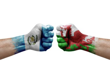 Two hands punch to each others on white background. Country flags painted fists, conflict crisis concept between guatemala and wales
