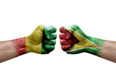 Two hands punch to each others on white background. Country flags painted fists, conflict crisis concept between guinea and guyana
