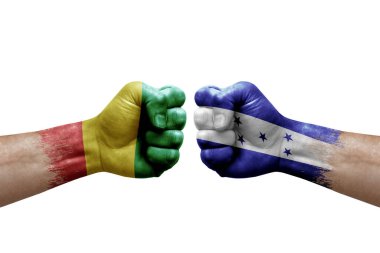 Two hands punch to each others on white background. Country flags painted fists, conflict crisis concept between guinea and honduras