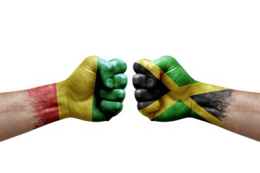 Two hands punch to each others on white background. Country flags painted fists, conflict crisis concept between guinea and jamaica