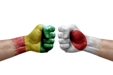 Two hands punch to each others on white background. Country flags painted fists, conflict crisis concept between guinea and japan