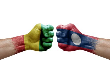 Two hands punch to each others on white background. Country flags painted fists, conflict crisis concept between guinea and laos