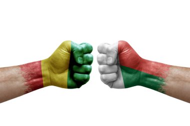 Two hands punch to each others on white background. Country flags painted fists, conflict crisis concept between guinea and madagascar