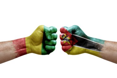 Two hands punch to each others on white background. Country flags painted fists, conflict crisis concept between guinea and mozambique