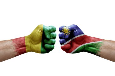 Two hands punch to each others on white background. Country flags painted fists, conflict crisis concept between guinea and namibia