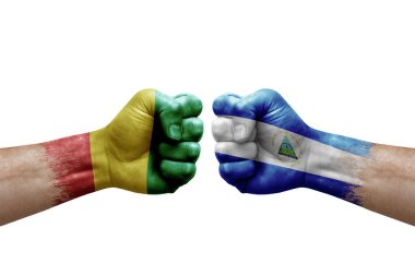 Two hands punch to each others on white background. Country flags painted fists, conflict crisis concept between guinea and nicaragua