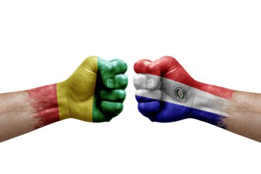 Two hands punch to each others on white background. Country flags painted fists, conflict crisis concept between guinea and paraguay