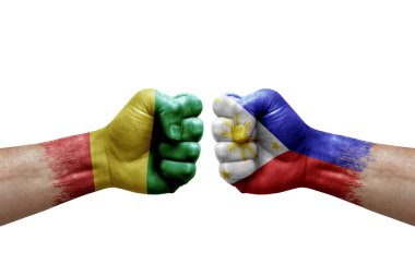 Two hands punch to each others on white background. Country flags painted fists, conflict crisis concept between guinea and philippines