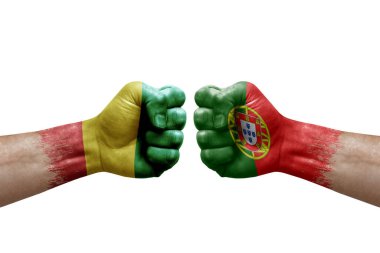 Two hands punch to each others on white background. Country flags painted fists, conflict crisis concept between guinea and portugal