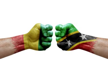 Two hands punch to each others on white background. Country flags painted fists, conflict crisis concept between guinea and saint kitts and nevis
