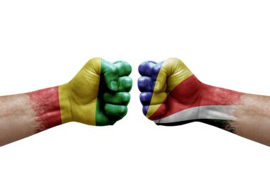 Two hands punch to each others on white background. Country flags painted fists, conflict crisis concept between guinea and seychelles