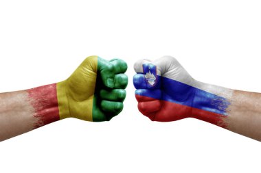 Two hands punch to each others on white background. Country flags painted fists, conflict crisis concept between guinea and slovenia